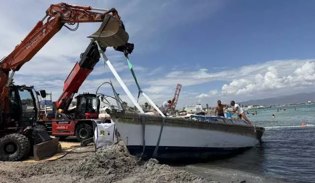 Al Poetto escavatore in azione per rimuovere la barca arenata (a due passi dai bagnanti): il video